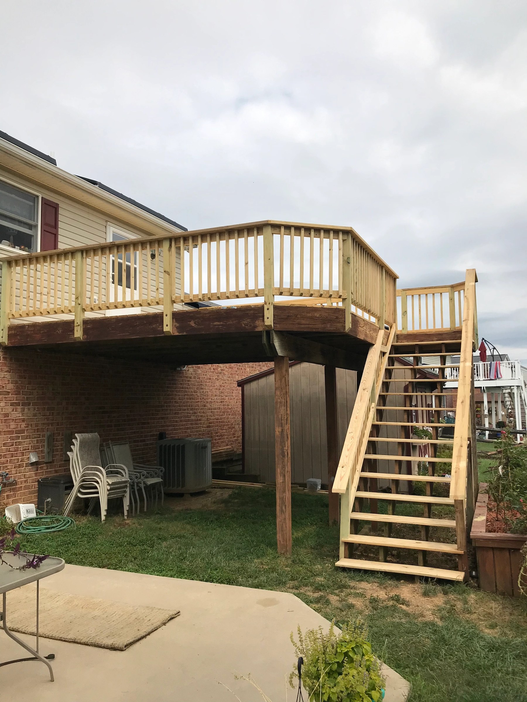 Elevated pressure-treated deck with new railing and a full stair run down to the garden