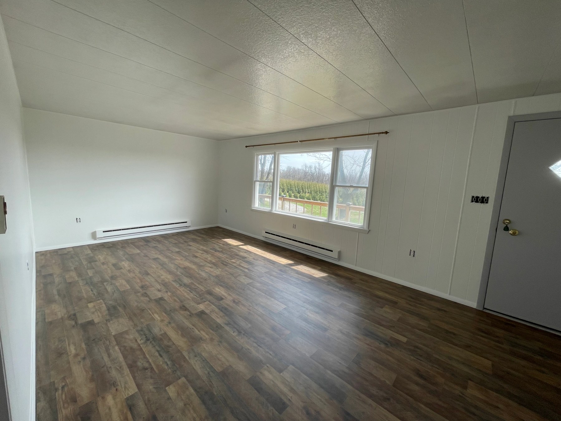 Refinished interior room with fresh white walls and new wood-look plank flooring