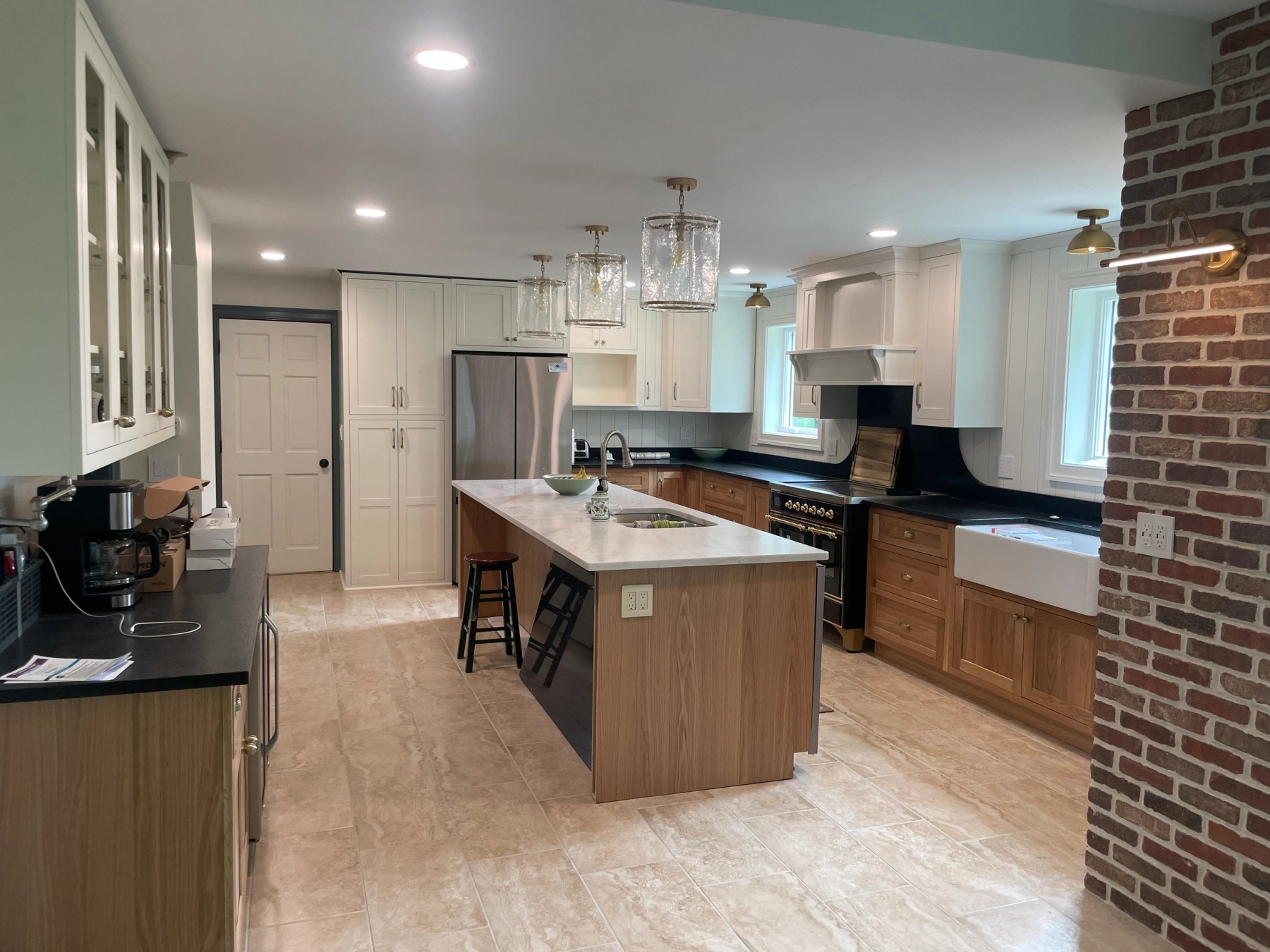 Finished open plan kitchen with a timber island, cream shaker cabinets and an exposed brick chimney